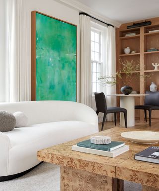White round sofa with green art piece in background