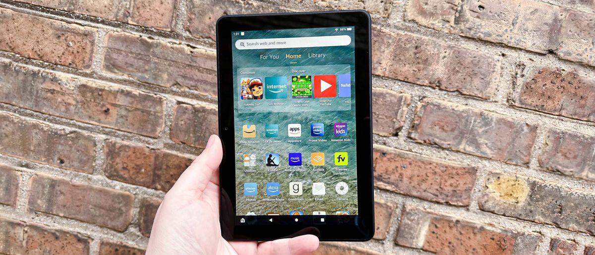 Amazon Fire HD 8 (2022) home screen pictured while held in hand in front of a brick wall