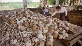 Haing Ngor and one other man with a pile of skulls and bones of executed victims of the Pol Pot regime.