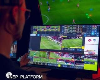 Man viewing screen with a soccer match in the distance.