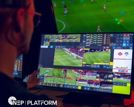 Man viewing screen with a soccer match in the distance. 