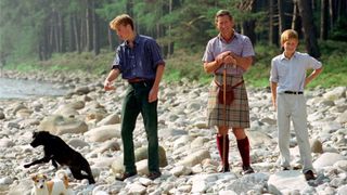 Prince Charles In Kilt And Sporran And Shepherd's Crook Walking Stick With Prince William & Prince Harry At Polvier, By The River Dee, Balmoral Castle Estate. Prince William's Dog Widgeon (black Labrador) And Prince Charles's Jack Russell Dog Called Tigga (tigger) Are With Them (Photo by Tim Graham Photo Library via Getty Images)
