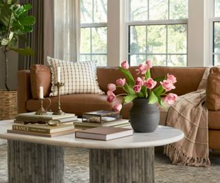 Brown leather sofa with gingham cushion and throw, marble coffee table and vase with roses