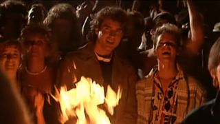 Jason Patric and Corey Haim smiling in front of a fire in The Lost Boys