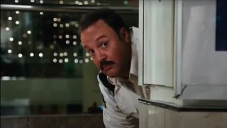 Kevin James peeking out with caution from a corner in Paul Blart: Mall Cop.