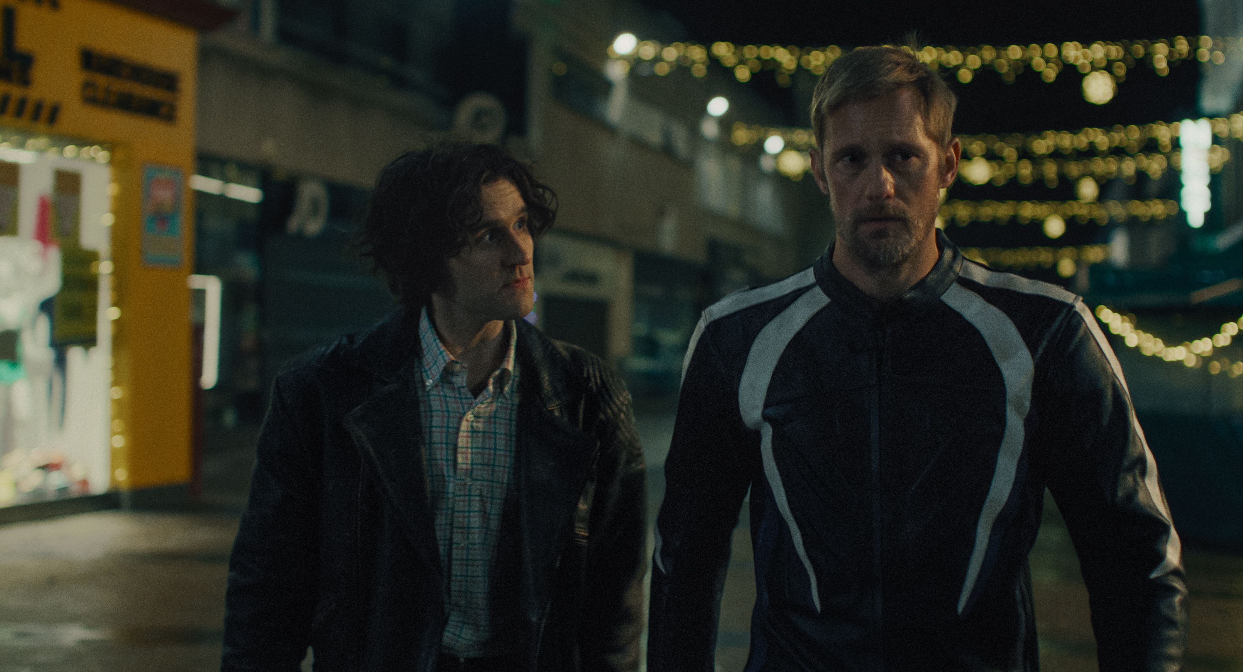 harry melling follows alex skarsgard in a biker moto jacket down a london street in the movie pillion