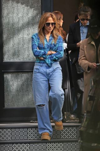 Jennifer Lopez leaving a tour of a potential new home wearing a plaid flannel shirt with ripped jeans and platform ugg boots