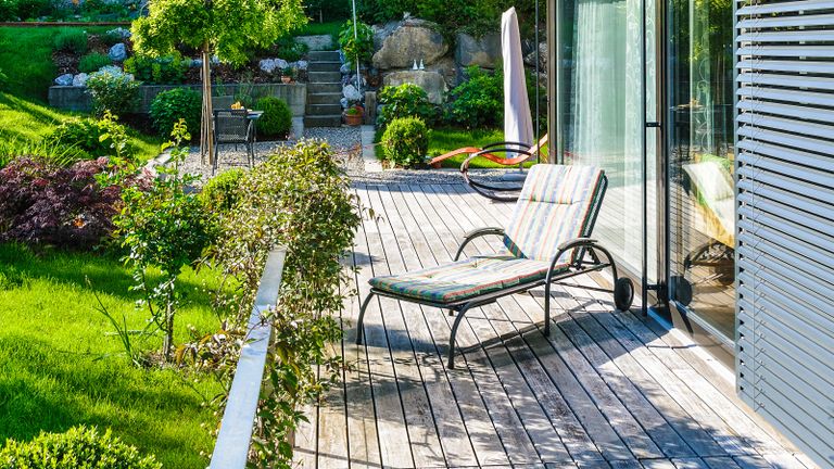 A wood deck with deck chair in residential backyard