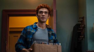 KJ Apa carrying a box of comics in Riverdale