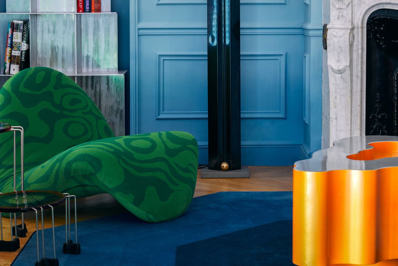 A living room with emerald green chair and deep blue carpet