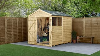 wooden shed in garden with windows, doors open on grey slabbed patio area