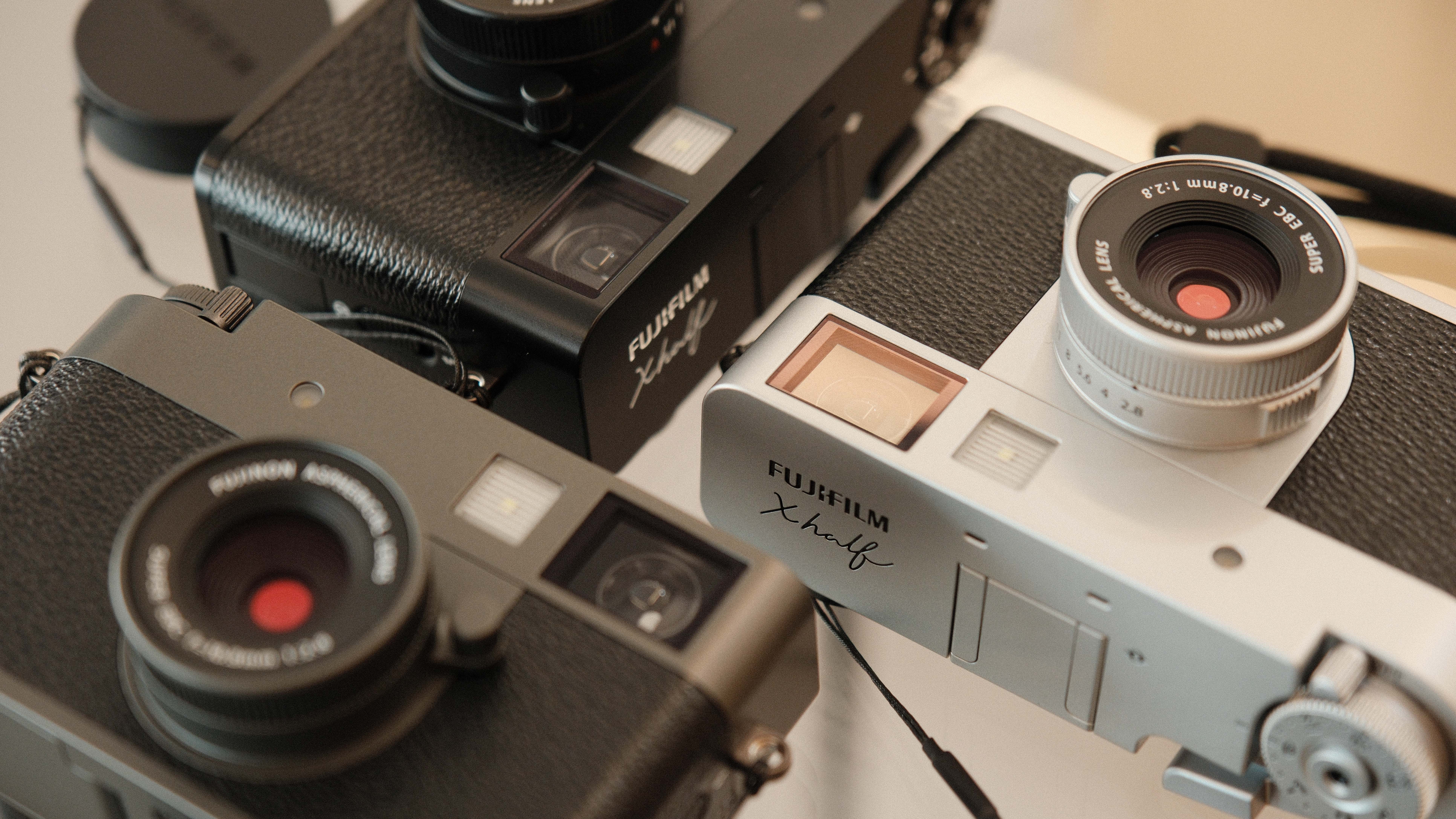 Close up of three Fujifilm X Half cameras in three different colors