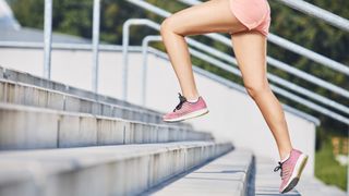 woman running up stairs outside in pink shoes and shorts