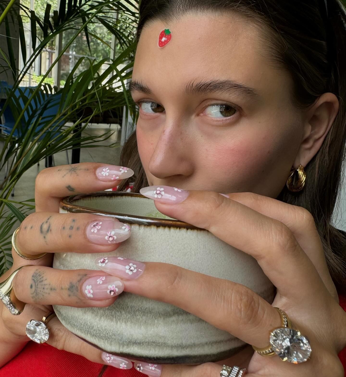 Hailey Bieber taking a selfie drinking tea with cherry blossom nails