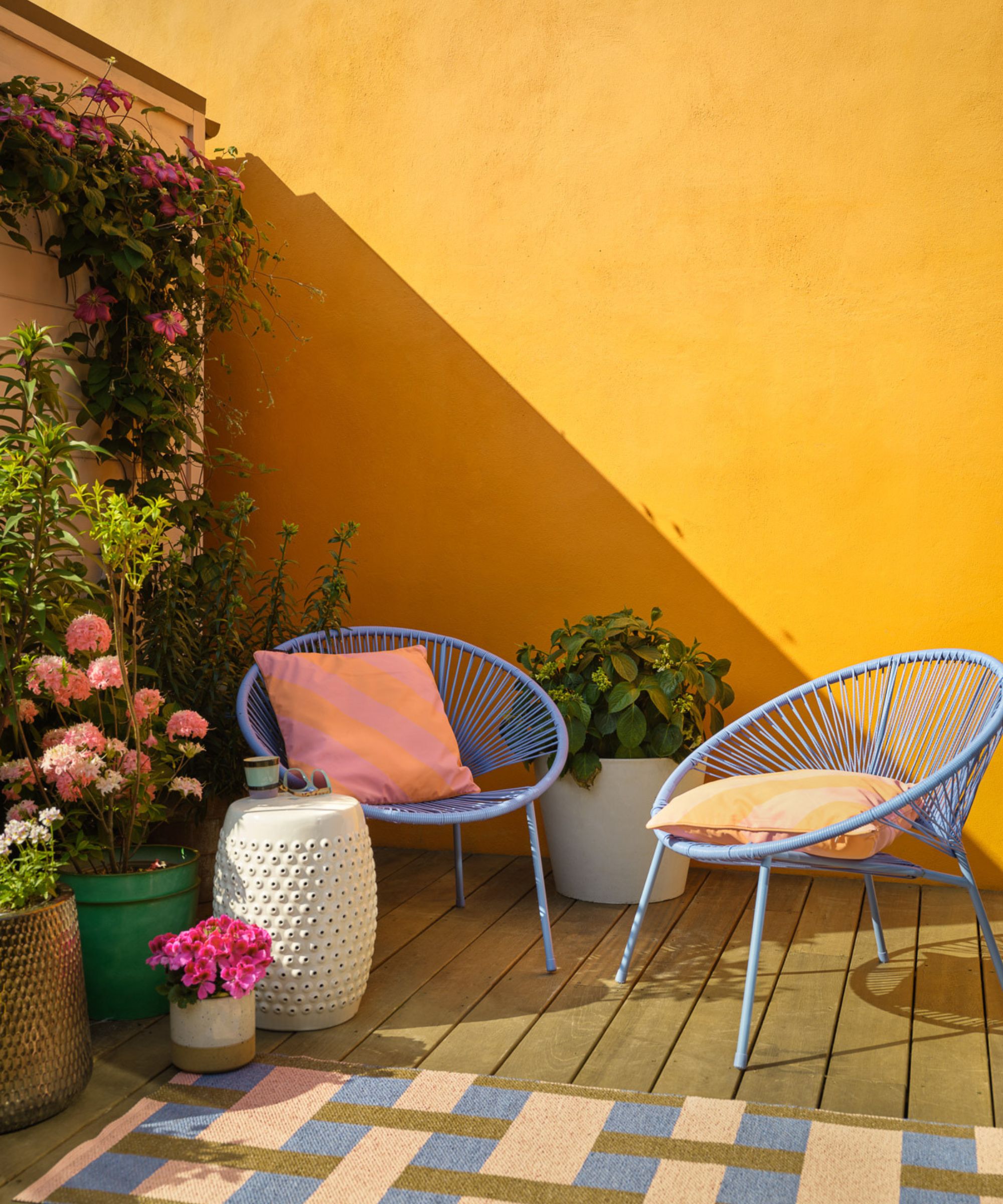 outdoor area with bright yellow wall and two blue chairs