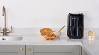 A tefal air fryer on a kitchen counter next to some cooking ingredients