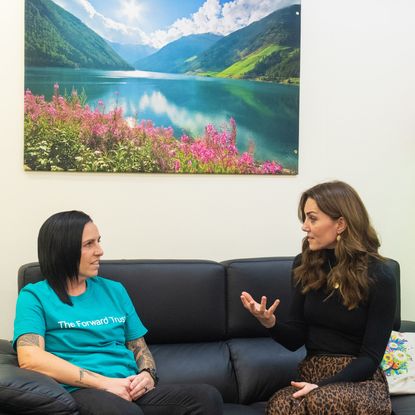 Kate Middleton wears a black top, a brown skirt, and black heeled boots to meet a prisoner