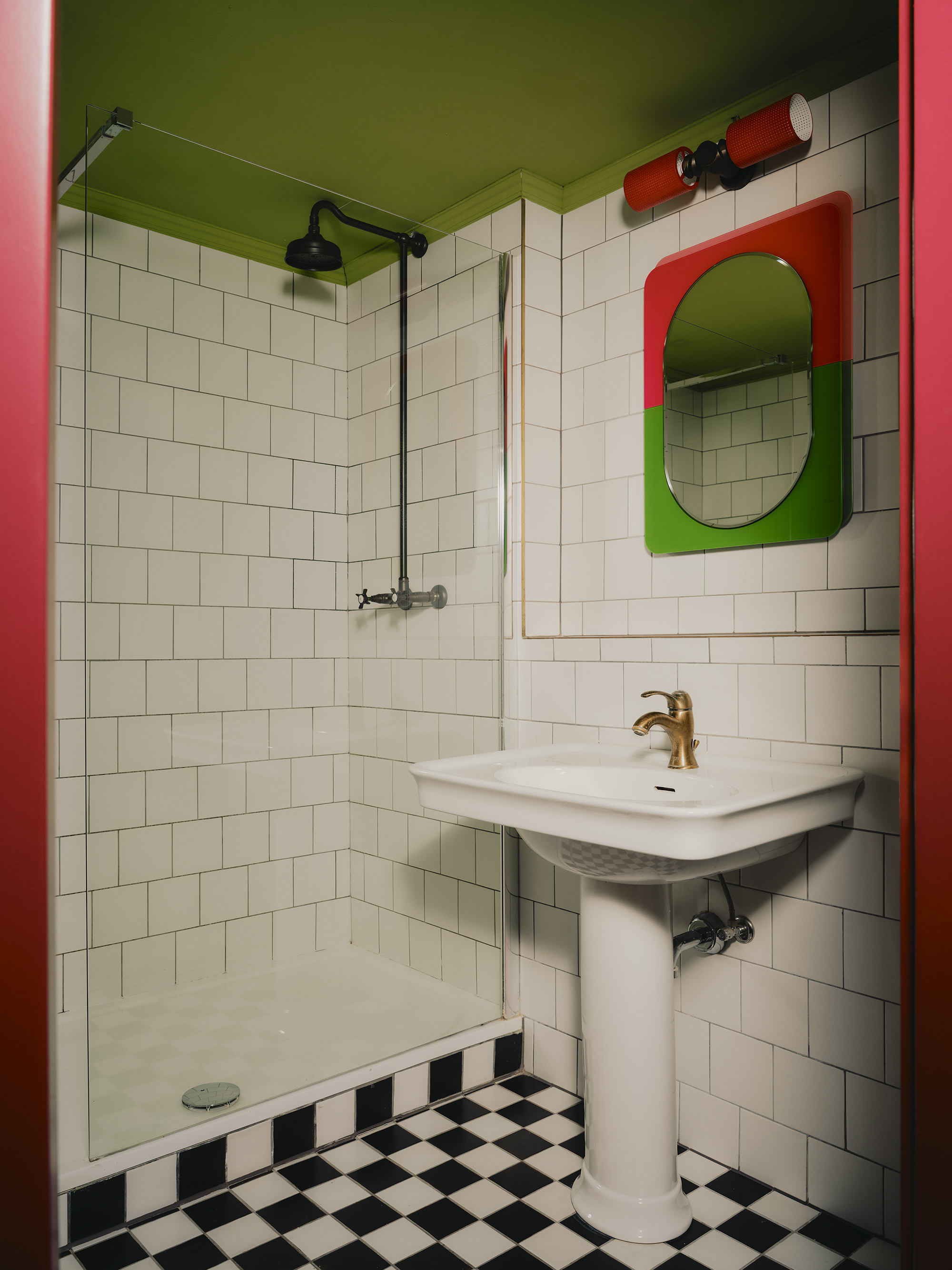 Interiors of a colorfully decorated hotel with a green, pink, and red palette, checkered or striped flooring, quirky, sculptural collectibles throughout, and lots of natural light.