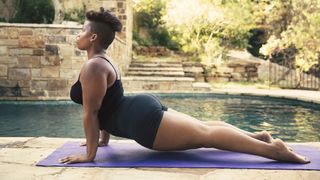 P.volve launches workout program tailored to each menstrual cycle phase: A in a black vest and shorts practices yoga next to a swimming pool