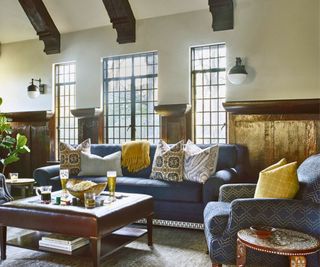 Blue sofa with assorted cushions in room with coffee table and windows behind