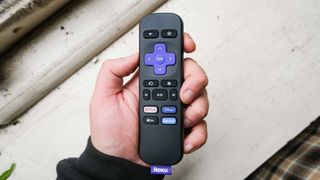 the Roku Express (2022) remote in hand over a white surface