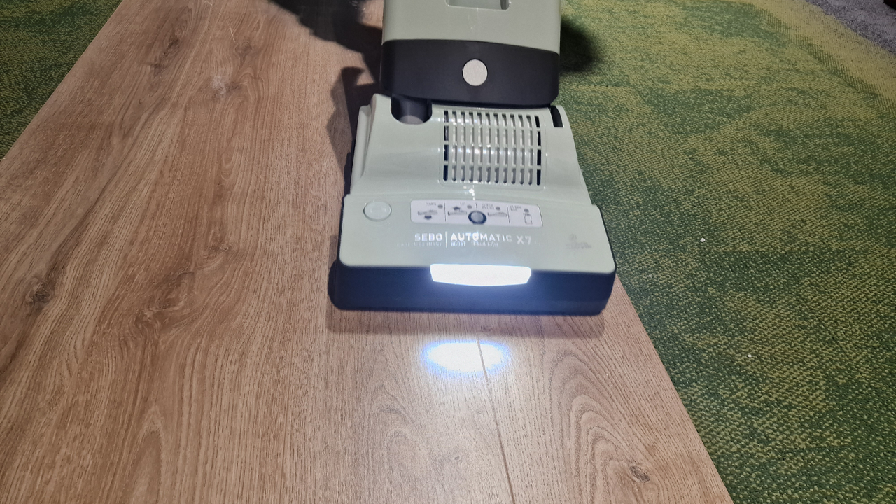 The SEBO vacuum sucking up hair from wooden floor