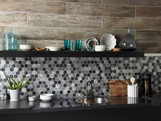 black, white and grey hexagonal backsplash tiles in a mosaic pattern in a dark kitchen