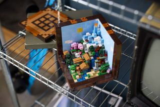Lego Minecraft Crafting Table on a shelf, a diorama of multiple Minecraft biomes can be seen inside the crafting table