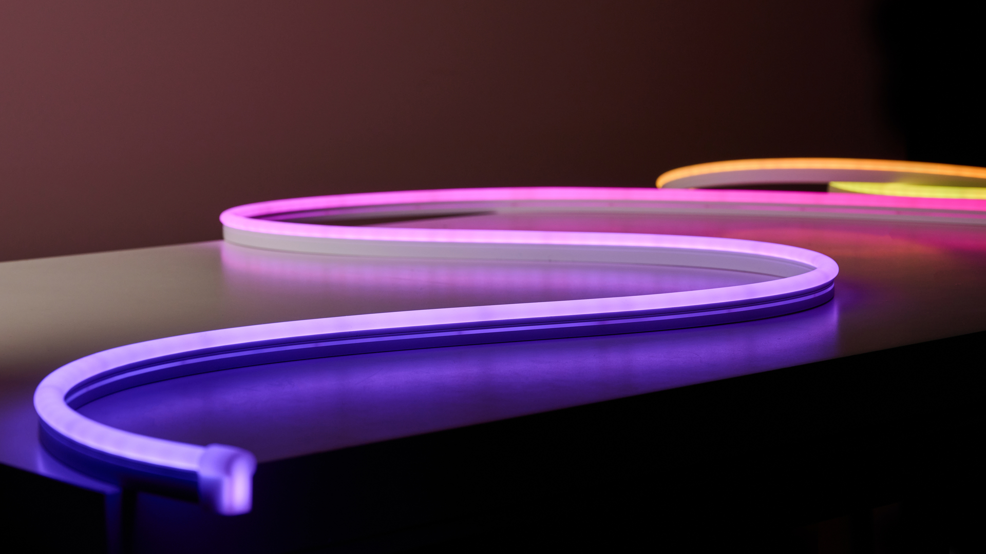 The rope light is snaked across a table, lit up in purple, pink, orange, and yellow.