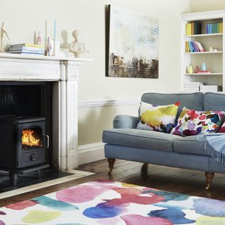 colourful rug, blue sofa and fire lit in woodburner