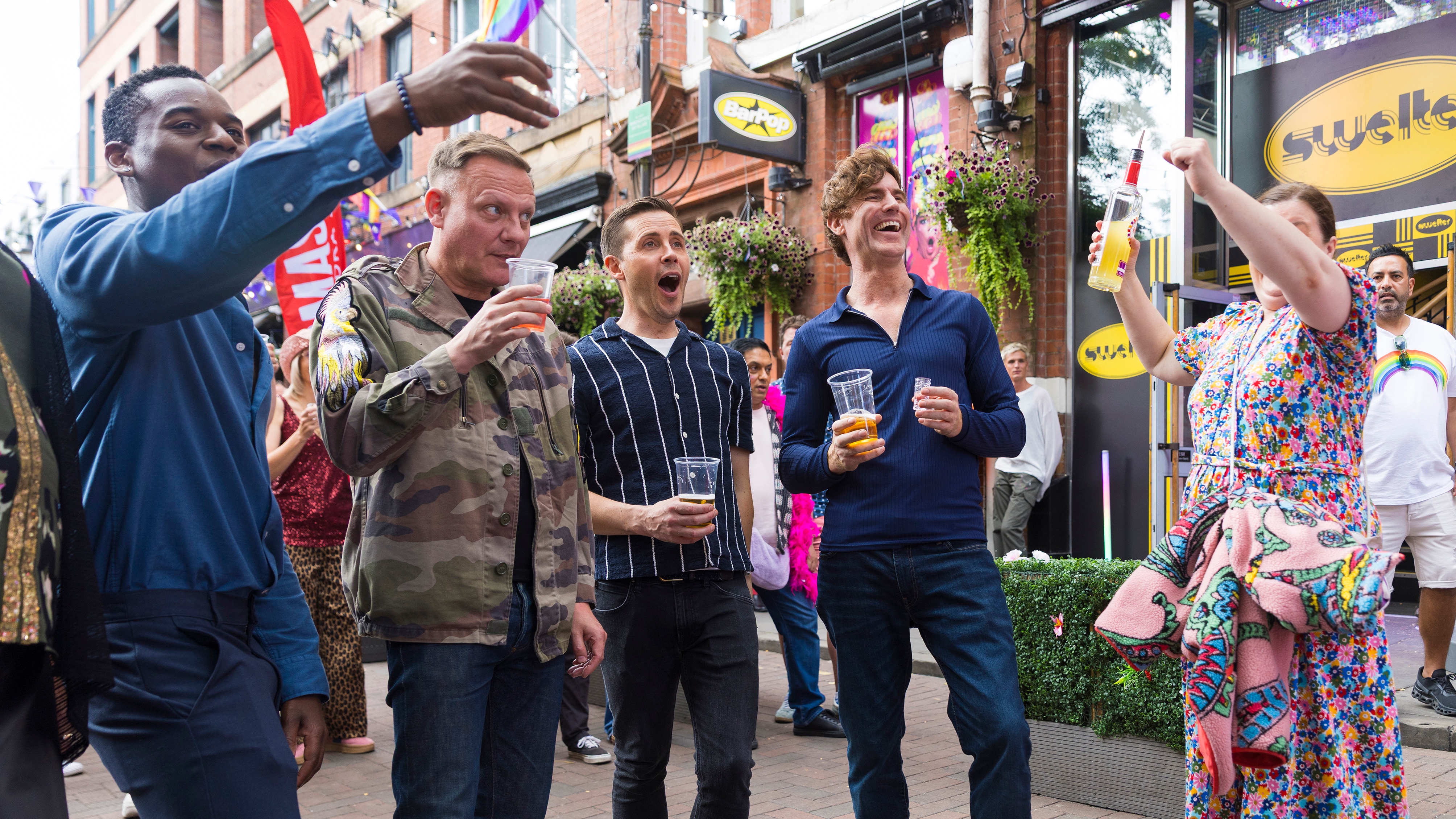 Theo, Sean, Mary and their friends having fun outside a bar, all holding drinks