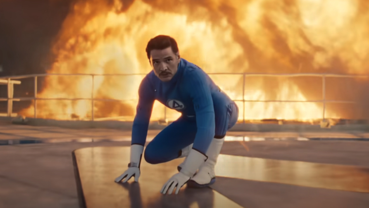 Pedro Pascal, leaping into action with fire blowing up behind him, as Reed Richards in The Fantastic Four: First Steps. 