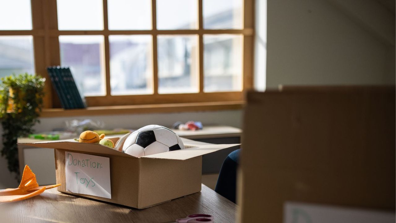 A box of toys on a bed with &#039;donation&#039; written on it