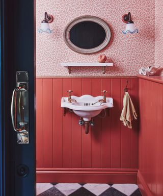 white wall mounted sink on pink panelled walls with floral wallpaper above panelling