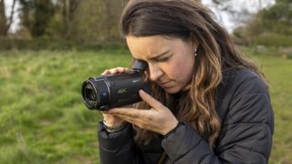 A female photographer looking into the Sony FDR-AX53 viewfinder