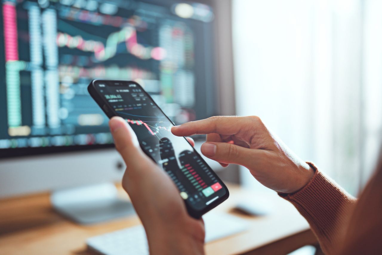 Woman checks investment performance on her smartphone.