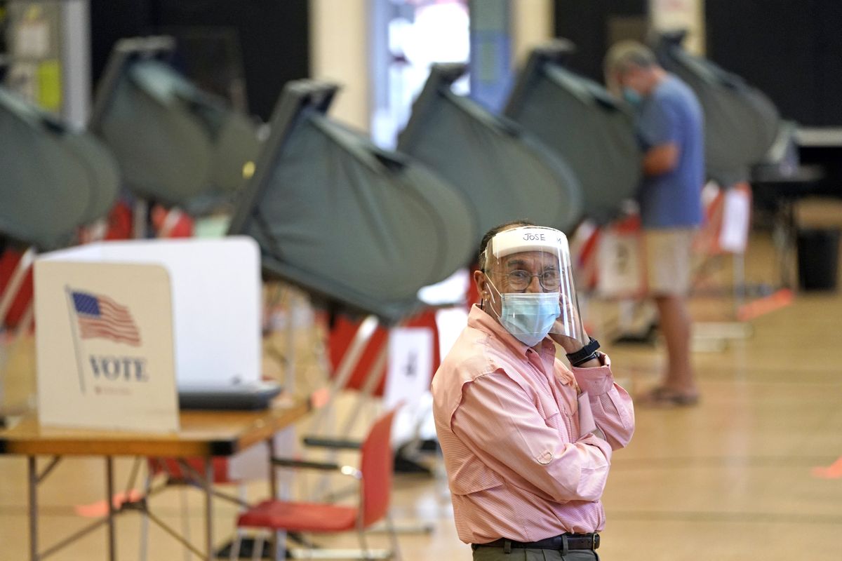 An election clerk in Harris County, Texas, watches over voting booths during early voting for the Texas primary runoffs.