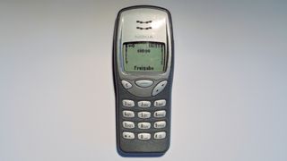 En Nokia 3210 mot en grå bakgrunn.