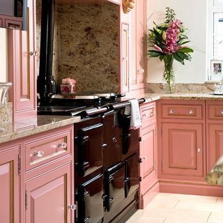 kitchen with pink cabinets flower vase and electric stove