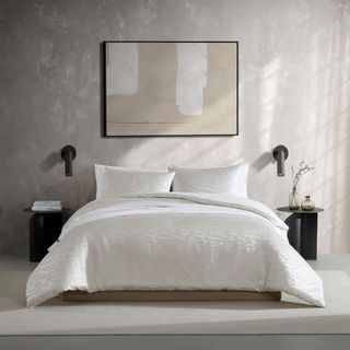 Vera Wang Duvet Cover Set on a bed with a nightstand either side against a beige wall.