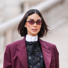 Heart Evangelista wears hair pins, a white shirt, a burgundy oversized blazer jacket , a black floral print mini dress , a black leather bag , outside Miu Miu , during the Womenswear Fall/Winter 2024/2025 as part of Paris Fashion Week on March 05, 2024 in Paris, France