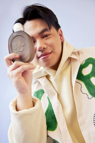 A model holds up a bottle of scent lab fragrance in front of a plain backdrop