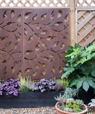 black planter with decorative metal panel on fence