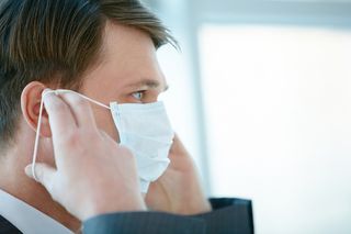 A man putting on a flu mask.