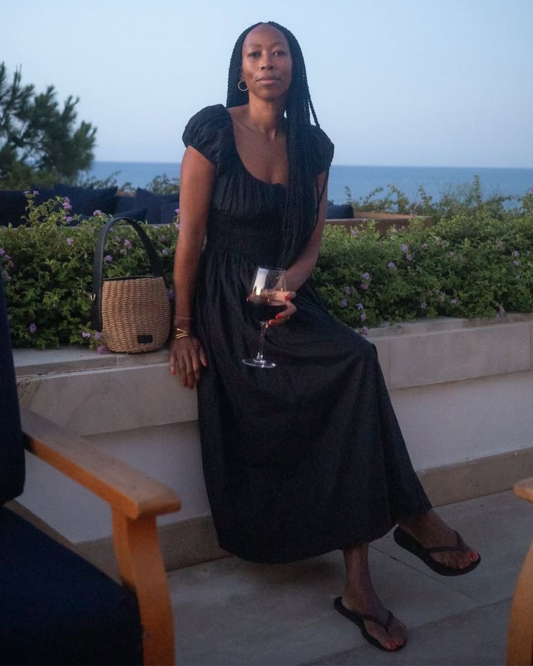@thandimaq wears a black midi dress and flip-flops