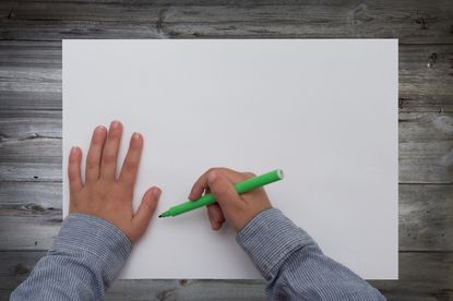 A boy writes on a piece of paper.