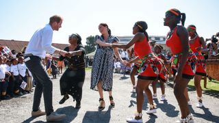 Prince Harry and Meghan Markle dancing with a tribe