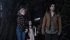 Julia Garner, Matilda Firth, and Christopher Abbott stand looking scared in a dark forest