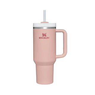 A pink tall Stanley Quencher metal coffee cup with a handle to the right, a white lid, and a white straw