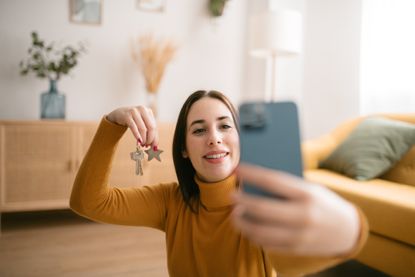 Young brunette woman taking selfie holding the key to her new apartment.